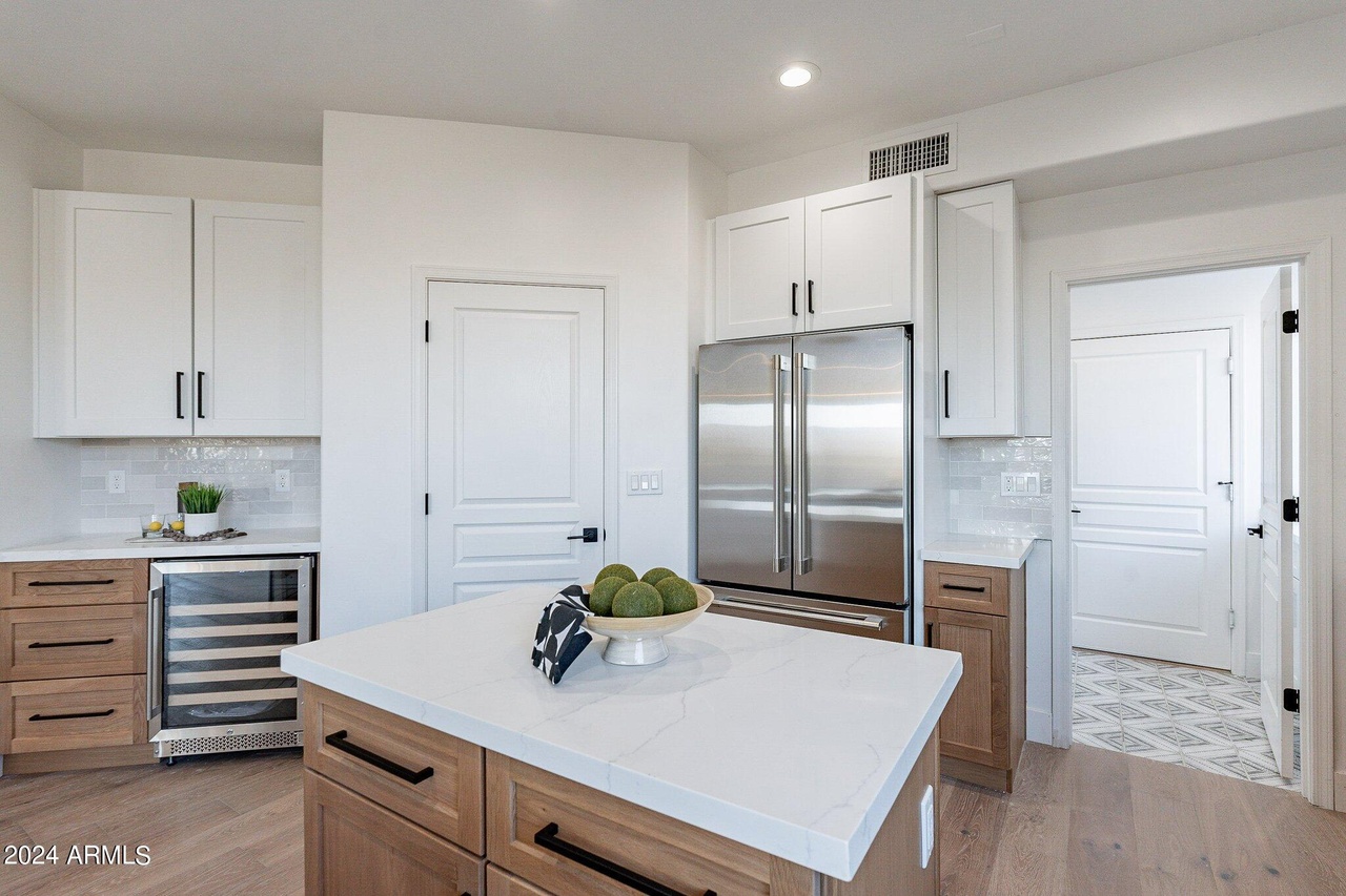 White shaker upper cabinets with natural wood lower cabinets and quartz island