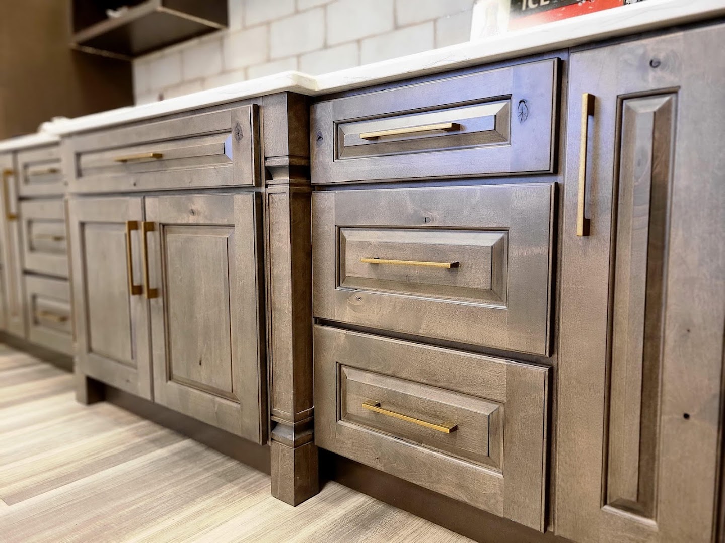 Gray-brown raised panel cabinets with brass hardware — showroom display