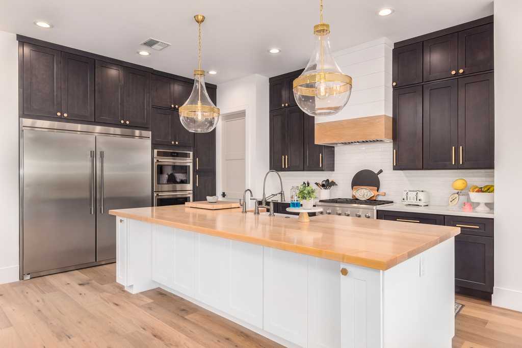 Dark espresso shaker cabinets with butcher block island and gold pendant lights